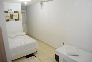 a white room with two beds in it at Lize Hotel in Campinas