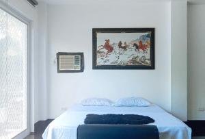 ein Schlafzimmer mit einem Bett und einem Gemälde an der Wand in der Unterkunft KrizLion Hotel in Hinatuan