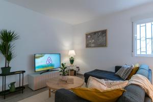 a living room with a blue couch and a tv at Satu Granada Modern Apartment in the Albaicín in Granada +27 photos