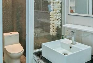 ein Badezimmer mit einem weißen Waschbecken und einer Toilette in der Unterkunft KrizLion Hotel in Hinatuan