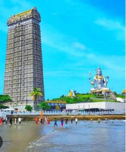 MāvalliShivaya AC & Non Ac Stay的海滩上的人们，背景是一栋高大的建筑。