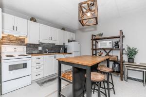 Una cocina con gabinetes blancos y una mesa de madera. en Alpine Cove - Condo in Collingwood - Sleeps 6, en Collingwood