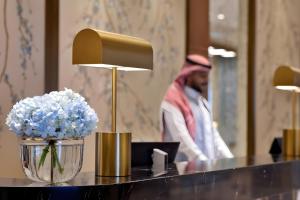 Una mesa con una lámpara y flores azules sobre ella. en Hilton Al Khobar King Fahd Causeway, en Al Khobar