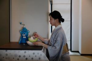 a woman is standing at a counter with a bowl at Stay Passport Sapporo Ryokan Seoul Hongdae in Seoul +108 photos