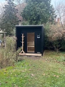Ein schwarzer Schuppen mit einer Bank im Hof. in der Unterkunft BIO Kastanienhof Erfurt - Appartements und ayurvedische Jurten in Erfurt