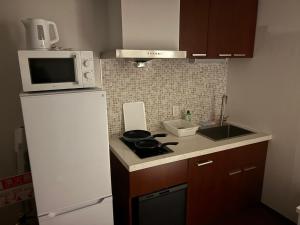 a kitchen with a white refrigerator and a microwave at Aparthotel STATUS SUSUKINO 102 in Sapporo