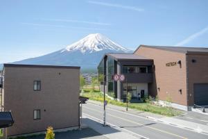 a snow covered mountain in the distance behind two buildings at GuestHouse　YOU&I in Fujikawaguchiko +108 photos