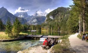 a group of people sitting at a table near a lake at Ferienhof Kandler in Rossleithen