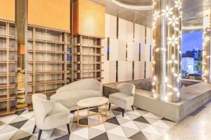 a lobby with chairs and a table and shelves at Sunday Hotel Arshika Sunset Road in Kuta