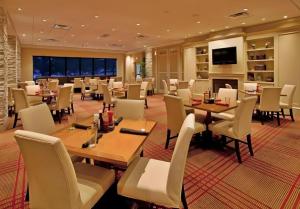 a restaurant with tables and chairs and a fireplace at Adam's Mark Hotel & Conference Center in Independence