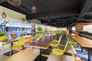a restaurant with wooden tables and green chairs at Sunday Hotel Arshika Sunset Road in Kuta