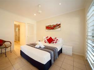 a bedroom with a bed with red pillows on it at Tropic Haven in Airlie Beach