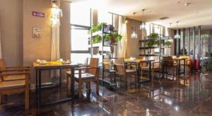 Un restaurante con mesas y sillas en una sala. en Xian Yi Jing Garden Hotel, en Xi'an