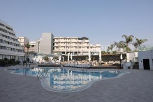 a swimming pool with chairs and buildings in the background at Sweet Sea Side Eilat - סוויט סי סייד, אילת in Eilat