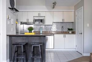 eine Küche mit weißen Schränken und einer Theke mit Stühlen in der Unterkunft Stay A While Ski-In-Out Hot Tub & Shuttle in Blue Mountains