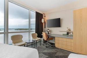 a hotel room with a bed and a desk with chairs at Clarion Lakeside Inn & Conference Centre in Kenora