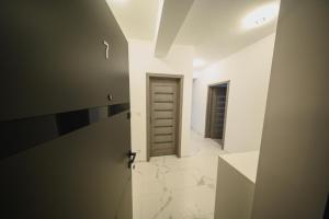 ein Badezimmer mit Tür und ein Flur mit Marmorboden in der Unterkunft Malvina Apartments Cazare Mures in Târgu Mureș + 24 Fotos