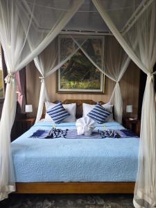 1 dormitorio con 1 cama azul con dosel en Tano Home Villas, en Ubud