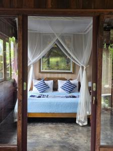 Un dormitorio con una cama con dosel y almohadas azules y blancas. en Tano Home Villas, en Ubud
