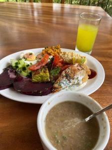 Un plato de comida con un tazón de sopa y un vaso de jugo de naranja. en Pilates Nosara, en Playa Guiones