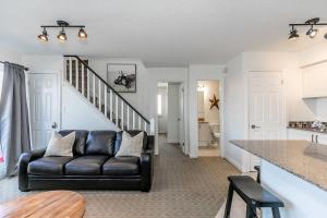 een woonkamer met een leren bank en een trap bij Mountain Peaks Ski-In-Out Pool Shuttle in Blue Mountains
