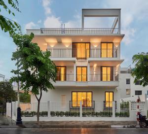 un edificio bianco con finestre e un albero di Villa Mystery Saigon ad Ho Chi Minh