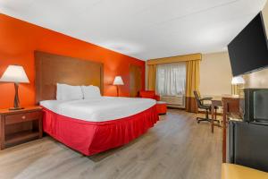 a hotel room with a large bed with an orange wall at Clarion Hotel & Conference Center Lansing West in Lansing +38 photos