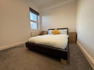 a bedroom with a bed with a yellow pillow on it at Belin Stay in Hackbridge