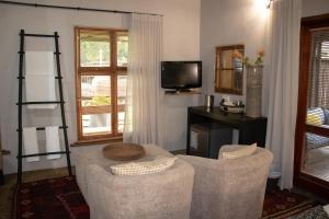 比勒陀利亚舍伍德小屋酒店的有两把椅子和一台电视的客厅