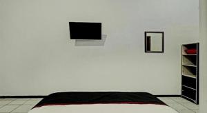 a bedroom with a bed and a white wall at Capital O 1362 Ciliwung Guest House Syariah in Malang
