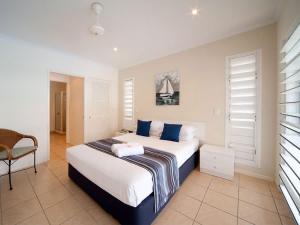 a bedroom with a large bed with blue pillows at Mermaids Mango House in Airlie Beach
