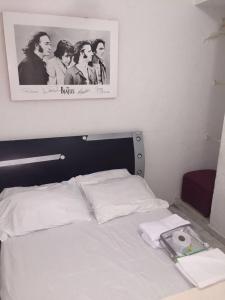 - un lit blanc dans une chambre avec une photo sur le mur dans l'établissement Hostel Mamy Dorme, à Barranquilla