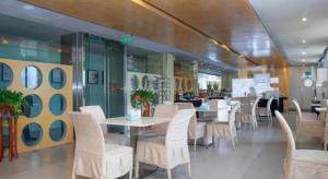 Un comedor con sillas y mesas blancas en un restaurante. en Jinjiang Inn Zhenjiang Jiangsu University Suning Plaza, en Zhenjiang