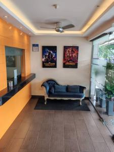 a living room with a blue couch and posters on the wall at Vitro Hotel in Johor Bahru