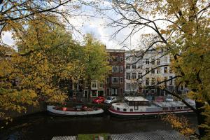 three boats are docked on a river in a city at The Townhouse Hotel in Amsterdam