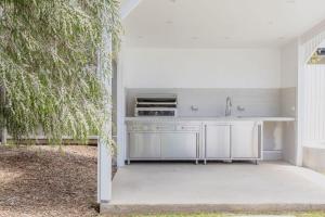 Coastal Waters - Spa, Sleeps 8, Newly Renovated في أوشن غروف: مطبخ مع حوض غسيل بجانب شجرة