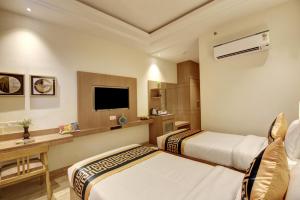 ニューデリーにあるHotel King Plazaのベッド2台とテレビがあるホテルの部屋