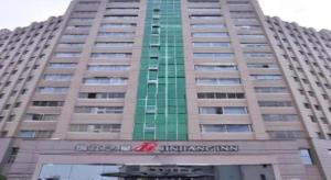 洛阳Jinjiang Inn Luoyang Nanchang Road Wangfujing的一座高大的建筑，窗户是绿色的。