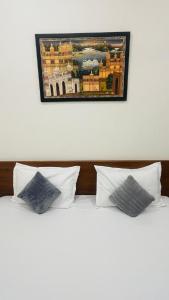 two white pillows on a bed with a picture on the wall at legacy of chittorgarh in Chittaurgarh +47 photos