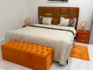 una camera da letto con un letto grande e una grande panca arancione di Le Prestige Appartement à Oloumi a Libreville