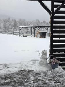 a snowman sitting in the snow next to a house at Zacisze w Karkonoszach in Karpacz
