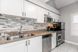 a kitchen with white cabinets and a stainless steel sink at Mountain View Ski-In-Out Pool Shuttle to Blue in Blue Mountains