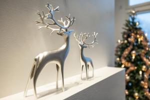 two metal deer statues on a shelf next to a christmas tree at Villa Lumossa - Lakeside Luxury with unique privacy in Rovaniemi