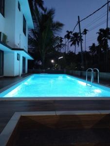 a large blue swimming pool at night at Bachan's Casa in Cherai Beach