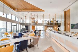 a restaurant with white tables and chairs and windows at The Quarter Ari by UHG in Bangkok
