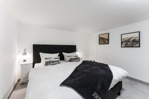 - une chambre blanche avec un grand lit et une couverture noire dans l'établissement Hüs Swarte Wall, à Kampen