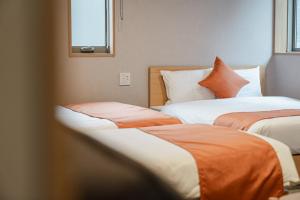 Dos camas con sábanas naranjas y blancas en una habitación. en グランドベースMirai, en Nagasaki 25 fotos más