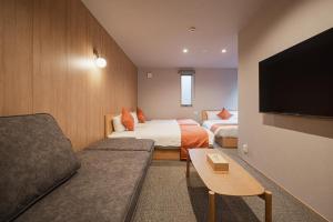 Una habitación de hotel con dos camas, un sofá y un televisor. en グランドベースMirai, en Nagasaki