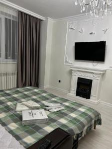 Квартира посуточно في أستانا: غرفة بسرير وموقد وتلفزيون