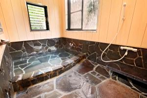 een jacuzzi in de hoek van een badkamer bij 旅館 家族湯 いまむら in Yamaga +18 foto's